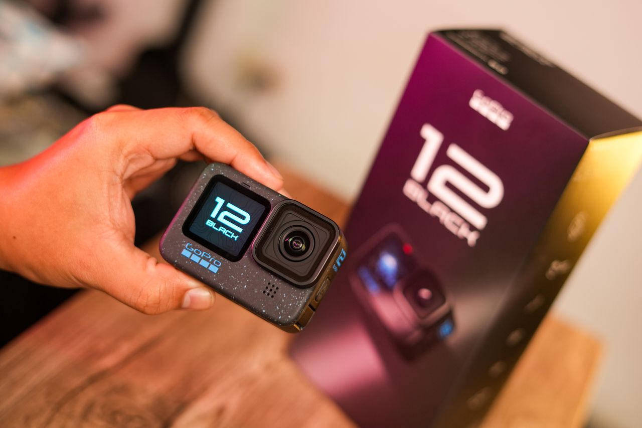 Close-up of a person holding an action camera with packaging box in the background.