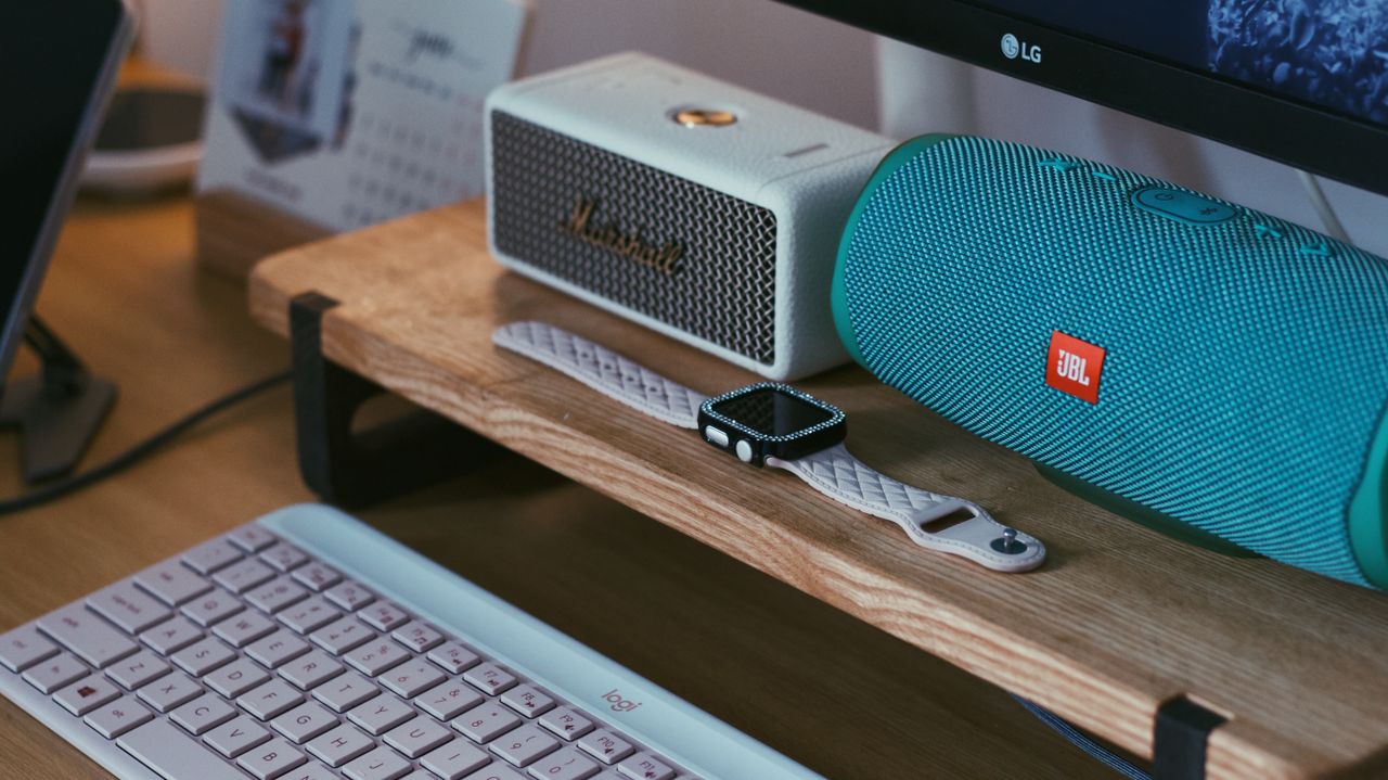 social-feed-img-01 A close-up of a modern workspace featuring Bluetooth speakers, a smartwatch, and a keyboard.
