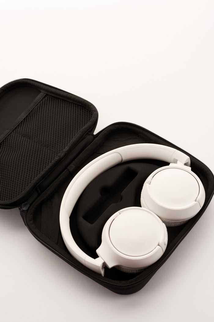 White headphones showcased in a black carry case on a neutral background, highlighting portability.