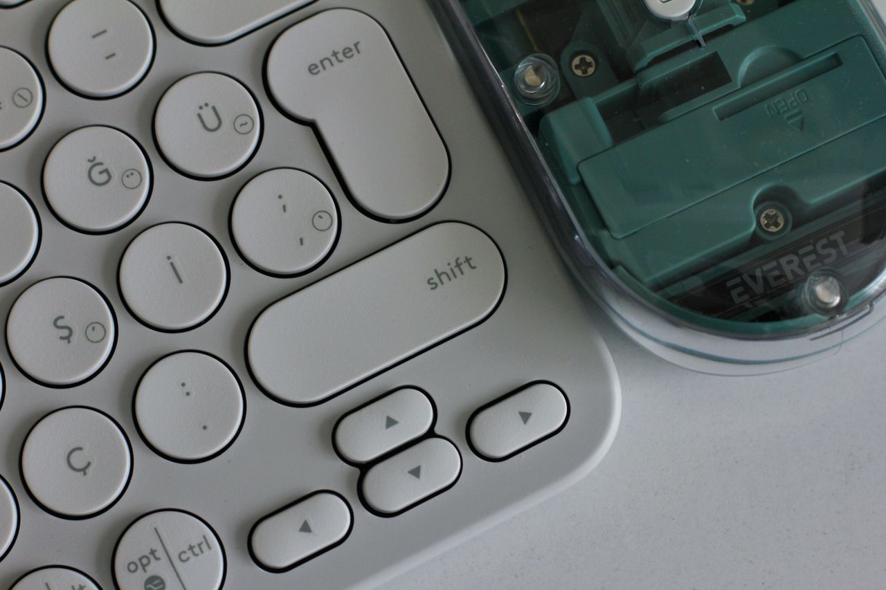Close-up photo of a wireless keyboard with circular keys and a transparent-bodied mouse, showcasing modern computer accessories.