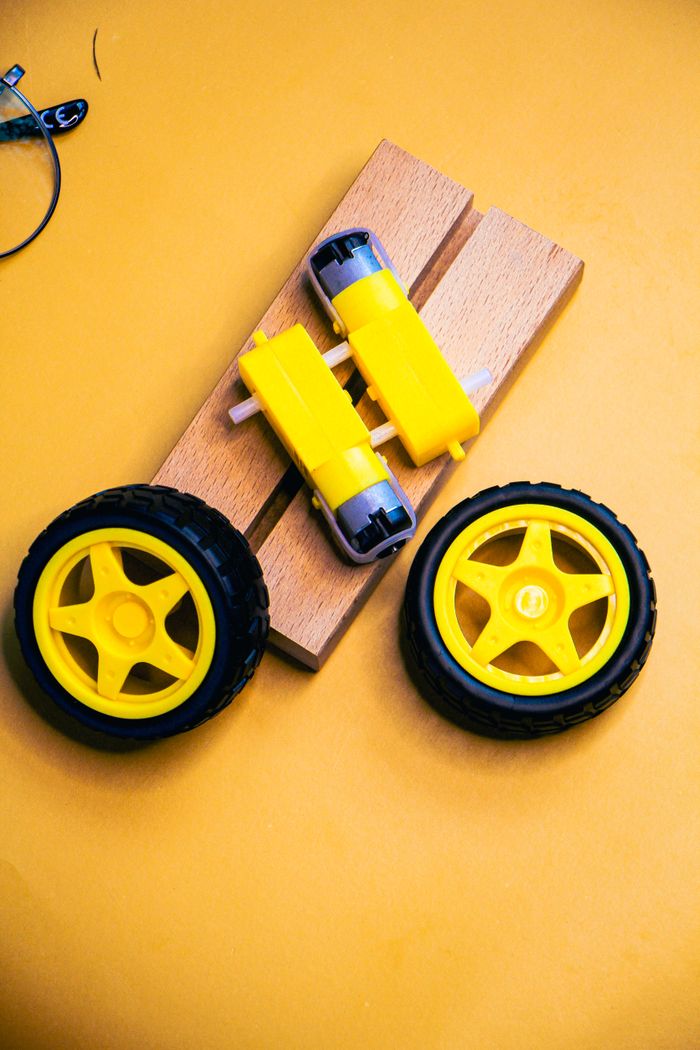 quality-assurance-01 Close-up of a robotics kit with yellow wheels and motors on a vibrant yellow background.
