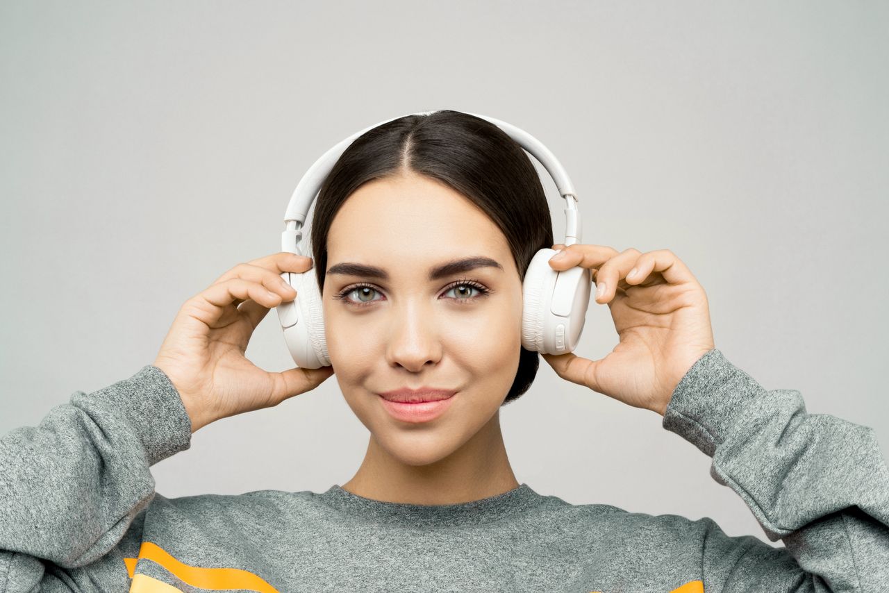 Young woman smiling while listening to music on headphones, creating a relaxed and joyful atmosphere.