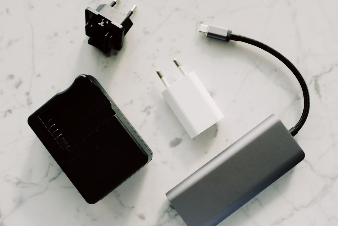 social-feed-img-02 A collection of electronic adapters and cables on a marble surface, showcasing tech essentials.