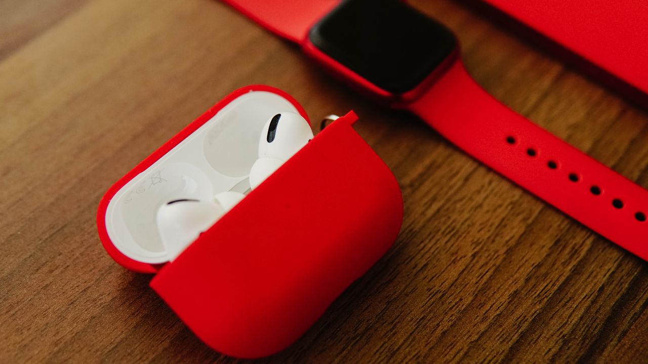 The Art of Drawing Readers In: Your attractive post title goes here Close-up of red AirPods and smartwatch on wooden surface for modern tech enthusiasts.